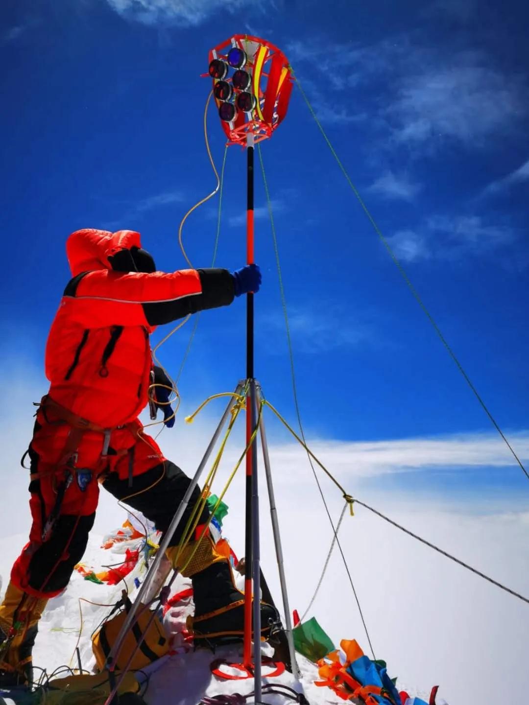 测量登山队员在峰顶立起觇标，连接华测导航北斗高精度定位设备